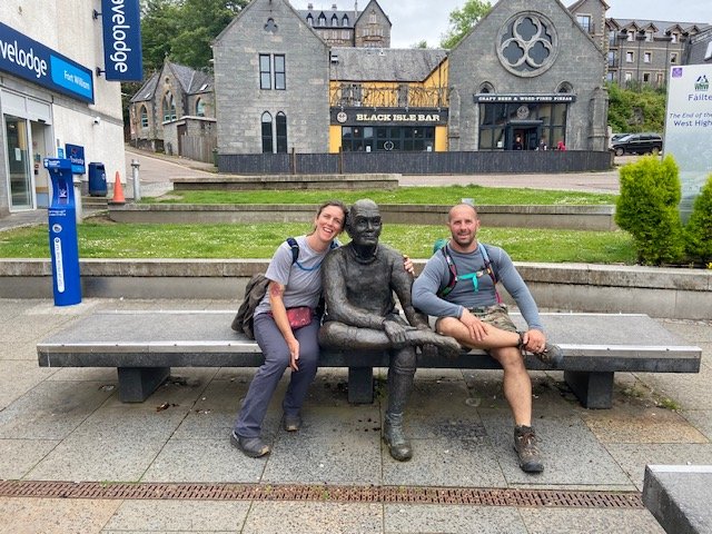 Erin and Scott on the bench with the walker statue in Gordon Square, Fort William